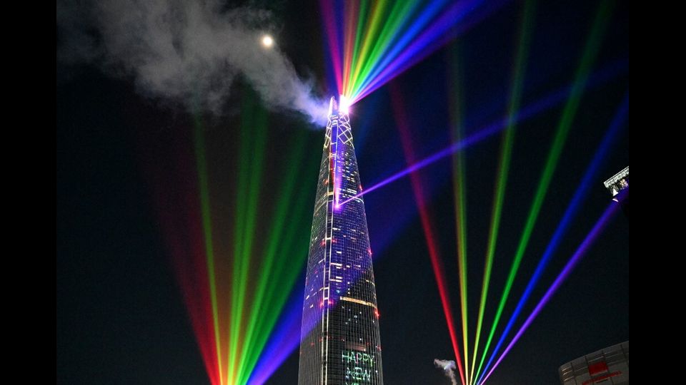 Le luci laser illuminano il cielo di mezzanotte sopra la Lotte World Tower, l'edificio più alto della Corea del Sud a Seul, durante i festeggiamenti di Capodanno del 1° gennaio 2026.