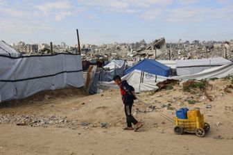 Un ragazzo sfollato vive tra le macerie delle case distrutte a Gaza dai raid dell'esercito israeliano