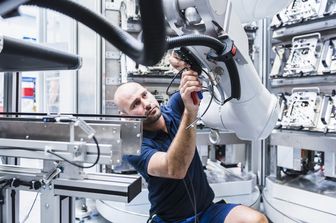 Un operaio al lavoro con un robot industriale.&nbsp;