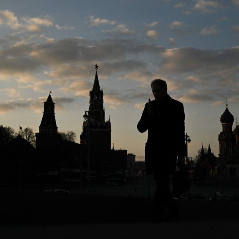 Un uomo cammina sul ponte Moskvoretsky con il Cremlino sullo sfondo