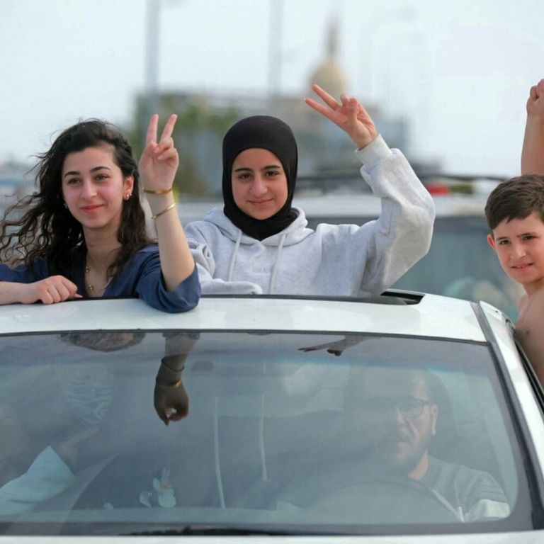 Gli sfollati attraversano la zona di Qasmieh, facendo il segno della vittoria mentre tornano alle loro case nel sud del Libano