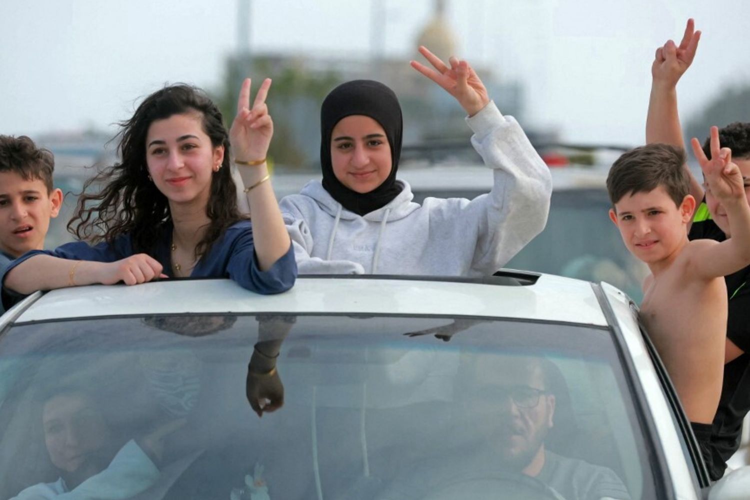 Gli sfollati attraversano la zona di Qasmieh, facendo il segno della vittoria mentre tornano alle loro case nel sud del Libano