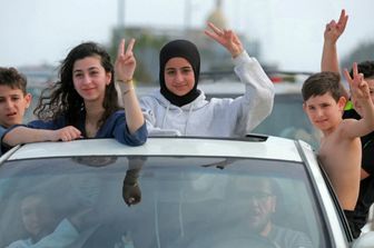 Gli sfollati attraversano la zona di Qasmieh, facendo il segno della vittoria mentre tornano alle loro case nel sud del Libano