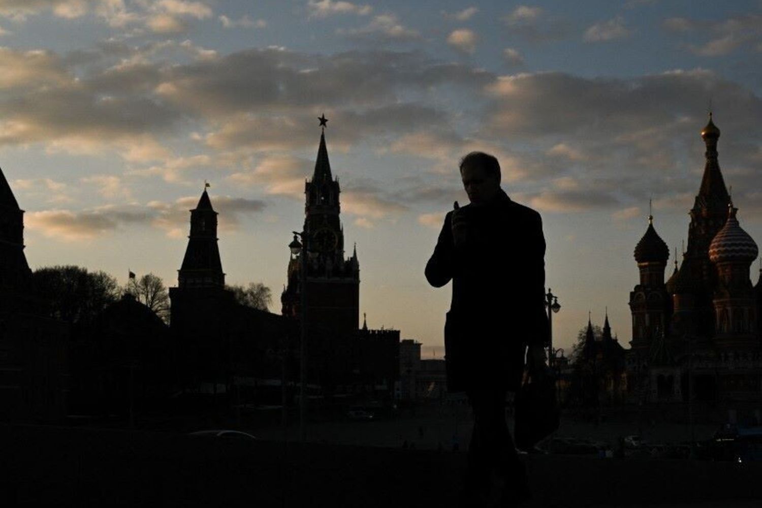 Un uomo cammina sul ponte Moskvoretsky con il Cremlino sullo sfondo