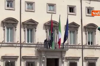 La bandiera libica viene sistemata sul balcone di Palazzo Chigi per la visita del premier Dbeibeh