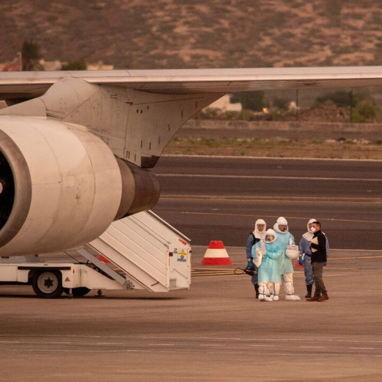 Alcune persone indossano tute protettive e si imbarcano a Tenerife su un aereo diretto negli Stati Uniti con a bordo i passeggeri evacuati dalla nave da crociera MV Hondius – immagine del 10 maggio 2026
