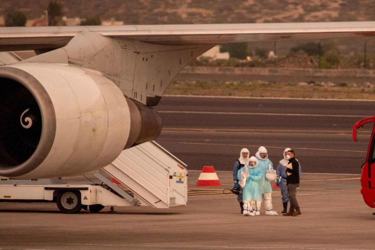Alcune persone indossano tute protettive e si imbarcano a Tenerife su un aereo diretto negli Stati Uniti con a bordo i passeggeri evacuati dalla nave da crociera MV Hondius – immagine del 10 maggio 2026