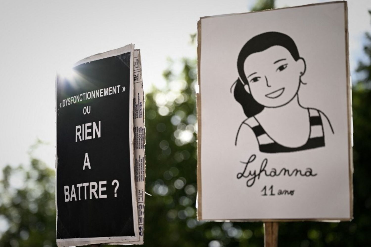 U n cartello con un'illustrazione raffigurante il ritratto della defunta Lyhanna (a destra) e un cartello con la scritta "'Un malfunzionamento' o semplicemente non vale la pena preoccuparsene?"