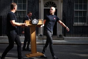 Alcuni membri dello staff portano il leggio fuori dal numero 10 di Downing Street – immagine del 22 giugno 2026