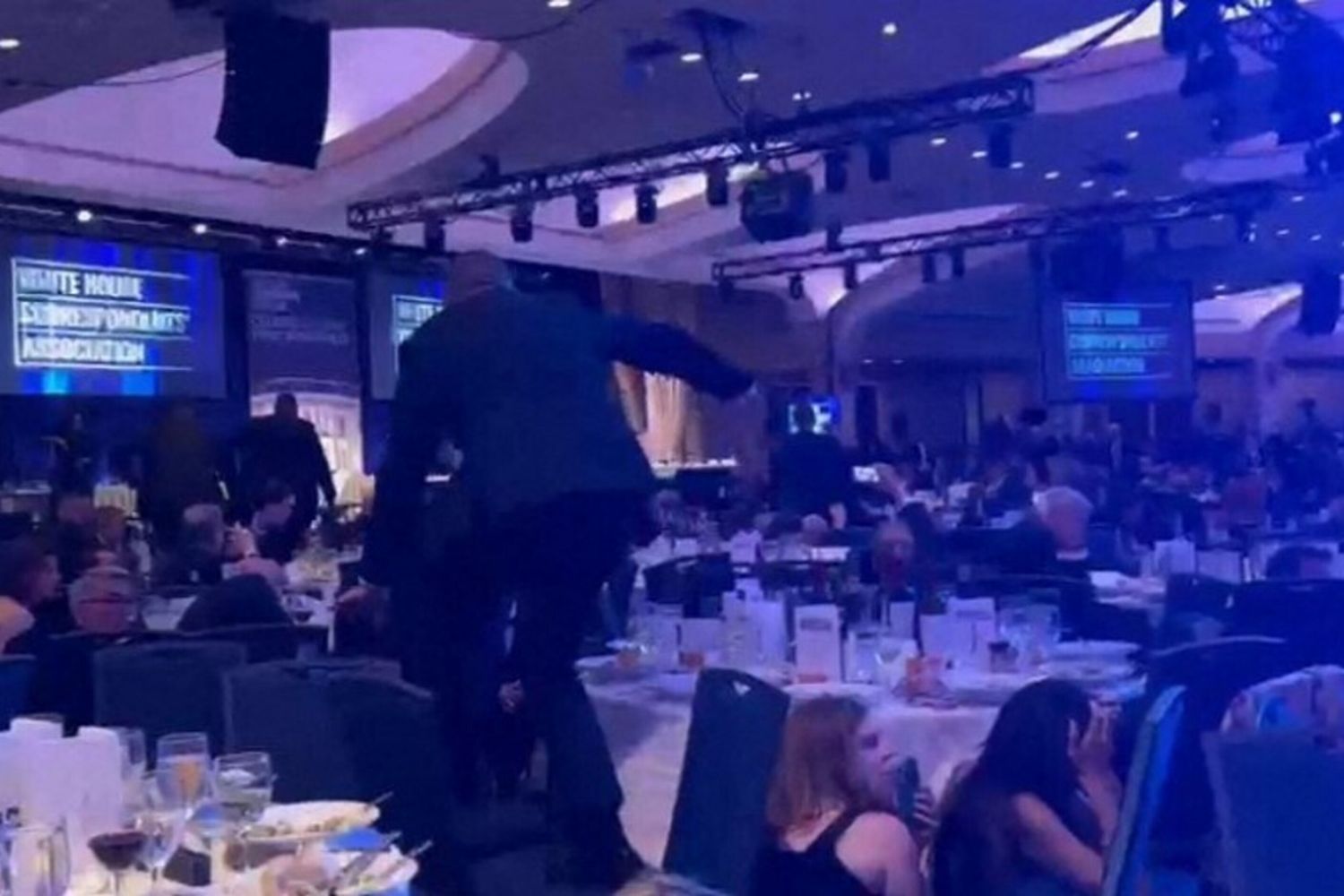 agenti armati che scavalcano le sedie mentre si dirigono verso il palco dopo che forti esplosioni sono state udite durante la cena dei corrispondenti della Casa Bianca al Washington Hilton