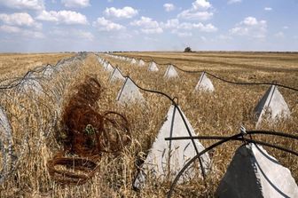 Una mietitrebbia raccoglie cereali lungo il filo spinato in un campo vicino a Orikhiv, nella regione di Zaporizhzhia in Ucraina