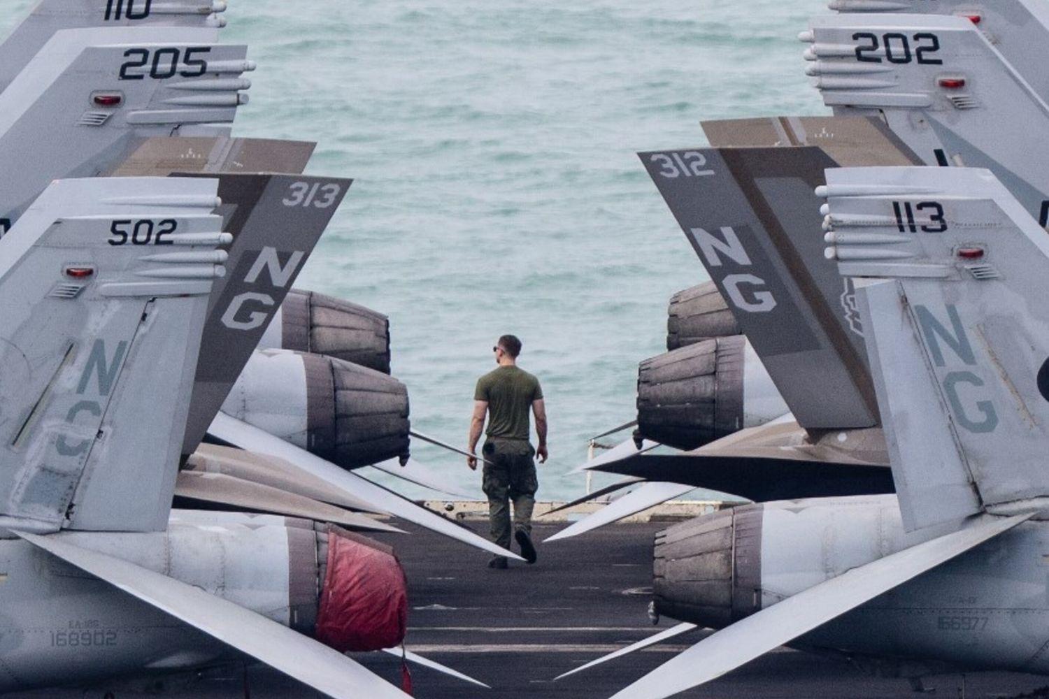 Un membro dell'equipaggio cammina sul ponte di volo della portaerei USS Abraham Lincoln mentre si dirige verso il porto di Pattaya