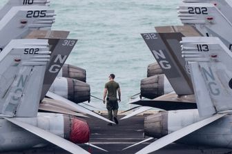 Un membro dell'equipaggio cammina sul ponte di volo della portaerei USS Abraham Lincoln mentre si dirige verso il porto di Pattaya