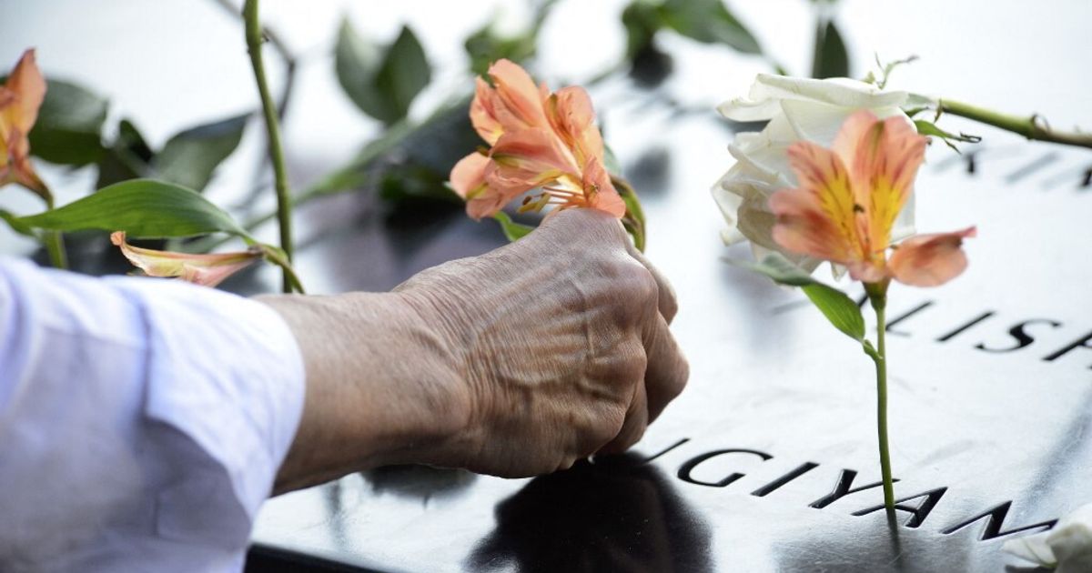 Una donna osserva volantini con i volti di vittime dell'11 settembre scomparsi nel vento a New York