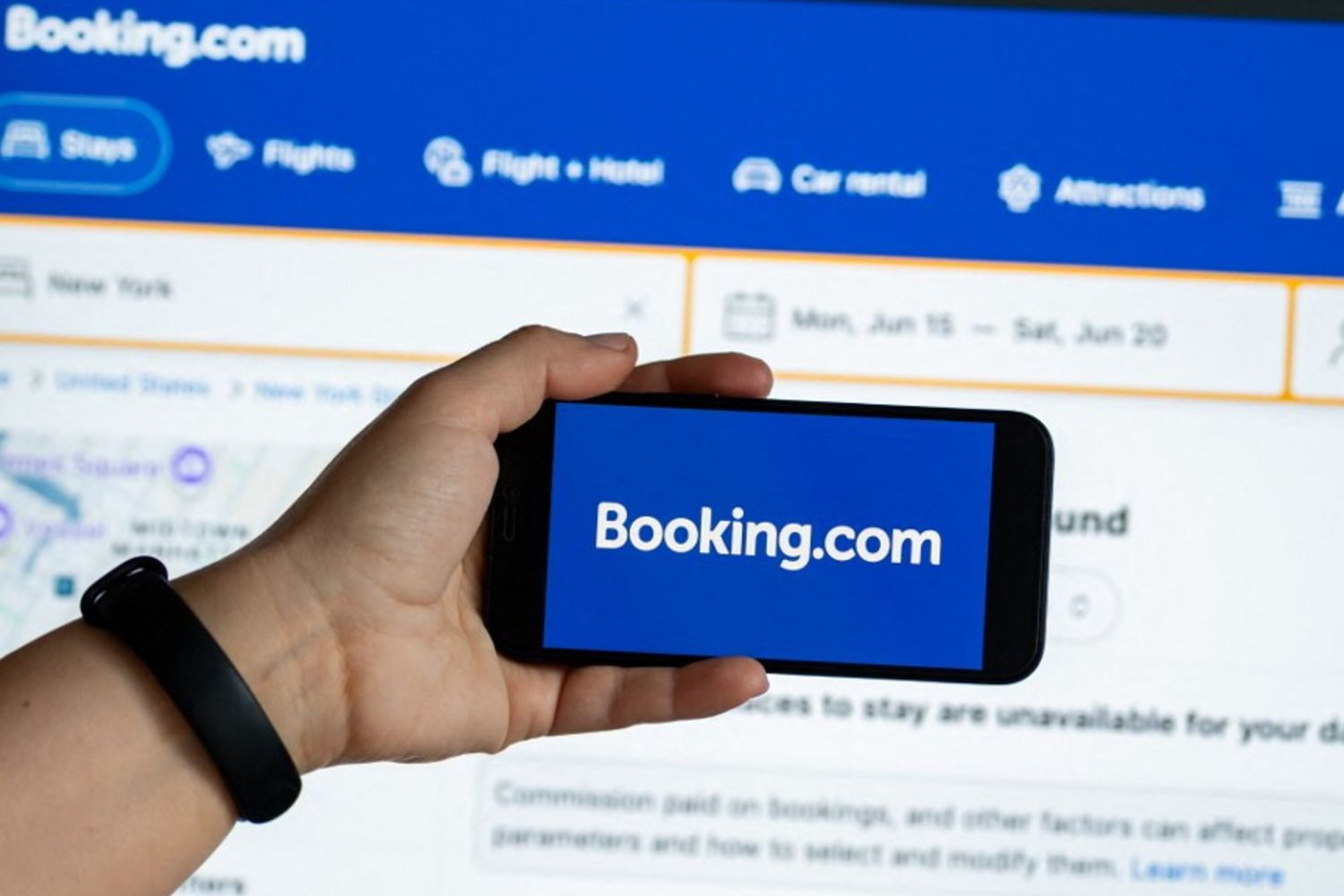 L'app Booking.com è visualizzata sullo schermo di uno smartphone e il sito web è visibile su un monitor di computer