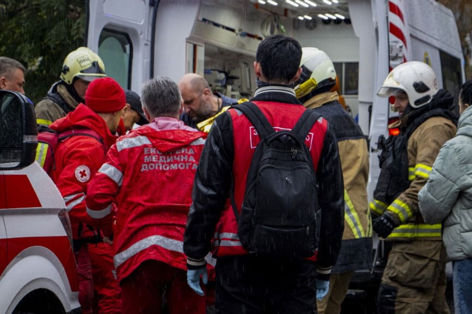 Soccorritori e vigili del fuoco si radunano vicino a un'ambulanza fuori da un edificio residenziale in Ucraina dopo un attacco russo
