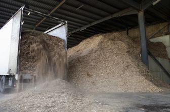 Rifiuti organici stoccati che vengono versati da un camion in un grande magazzino per la produzione di combustibile a biomassa in Inghilterra